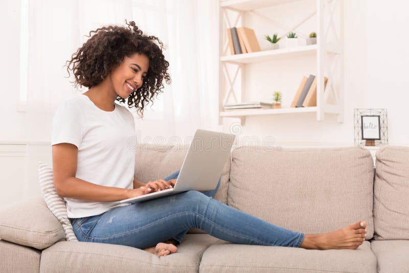Mulher afro-americano que trabalha no laptop em casa