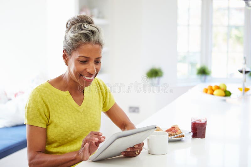 Mulher afro-americano que usa a tabuleta de Digitas em casa imagem de stock Mulher afro-americano que usa a tabuleta de Digitas em casa imagem de stock