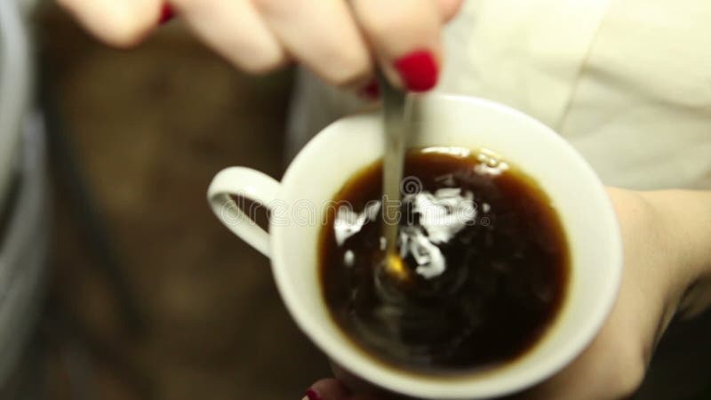 A mulher agita o café, close-up