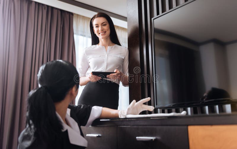 Mulher alegre atrativa que olha a empregada doméstica do hotel foto de stock Mulher alegre atrativa que olha a empregada doméstica do hotel foto de stock