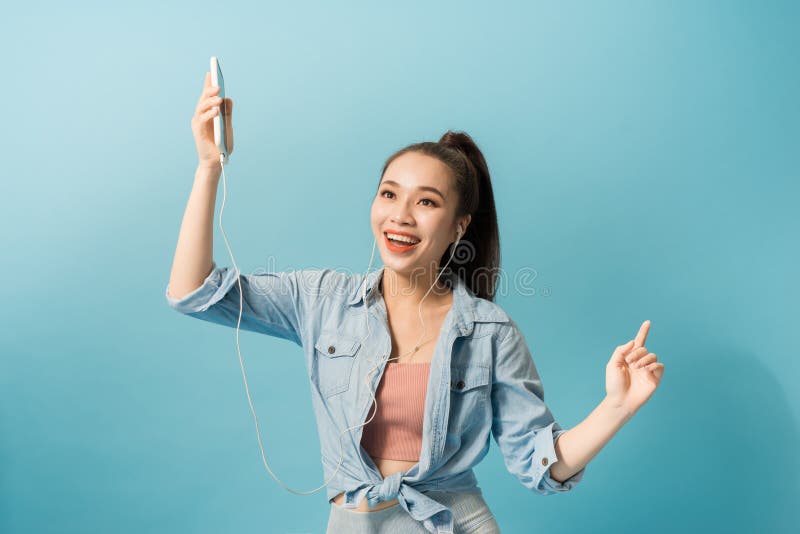 Mulher alegre nos fones de ouvido que escuta a música e a dança isolada sobre o fundo azul fotos de stock Mulher alegre nos fones de ouvido que escuta a música e a dança isolada sobre o fundo azul fotos de stock