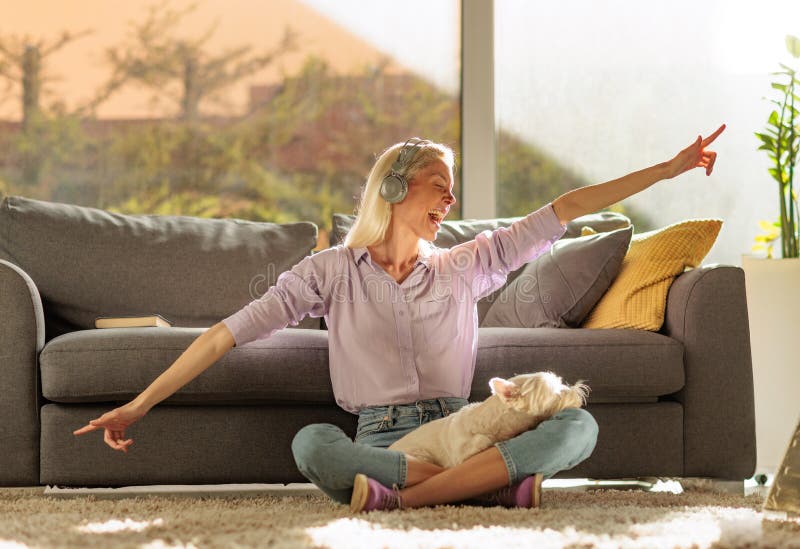 Mulher alegre sentada no chão com um West Highland White Terrier no colo imagens de stock royalty free