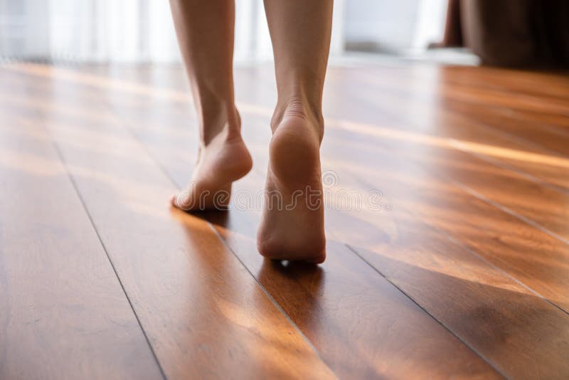 Mulher andando descalça sobre os dedos na vista de vestir o chão quente
