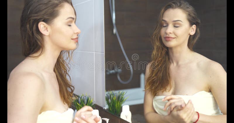 Mulher Bonita E Satisfeita Olhando Para O Espelho No Banheiro, Sentindo-se Bonita E Atraente, Menina Feliz Usando Roupão Branco Tocando A Pele Lisa Perfeita Do Rosto, Desfrutando Da Rotina De Cuidados Com