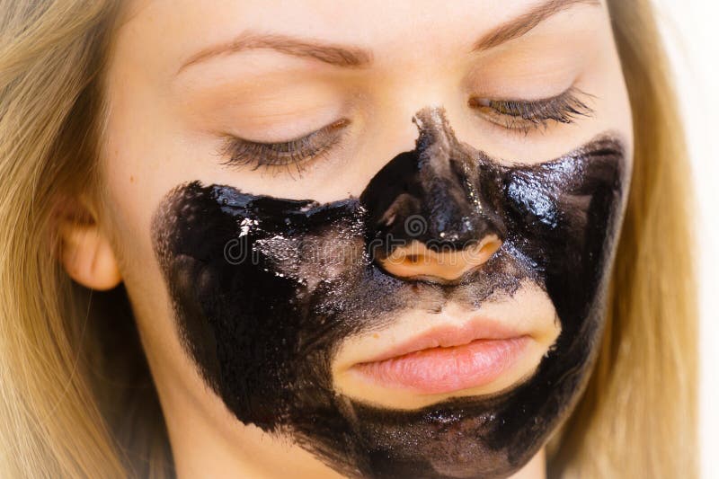 Mulher a aplicar máscara de limpeza preta no rosto foto de stock royalty free