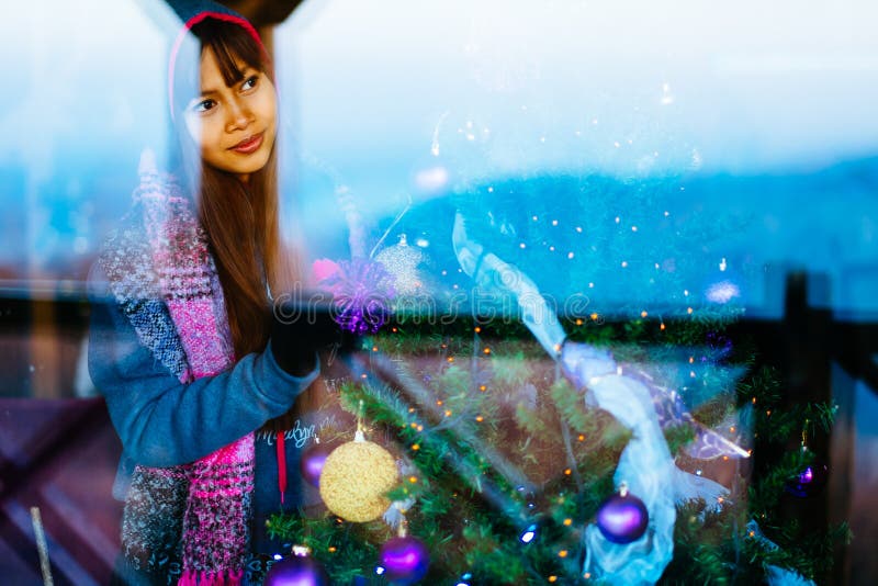 Mulher asiática bonita nova no revestimento do inverno, decorando a árvore de Natal em casa Calha do tiro do retrato da jovem mul imagem de stock Mulher asiática bonita nova no revestimento do inverno, decorando a árvore de Natal em casa Calha do tiro do retrato da jovem mul imagem de stock