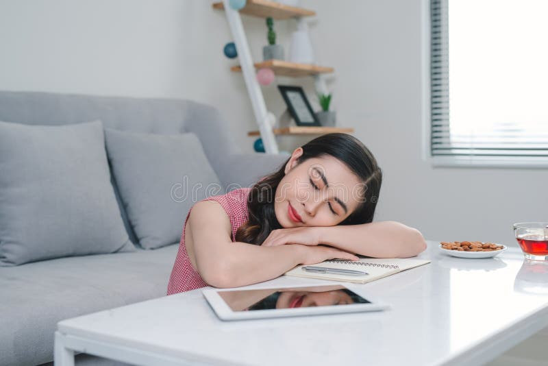 Mulher asiática cansado que dorme perto do sofá após o trabalho em casa imagens de stock royalty free Mulher asiática cansado que dorme perto do sofá após o trabalho em casa imagens de stock royalty free
