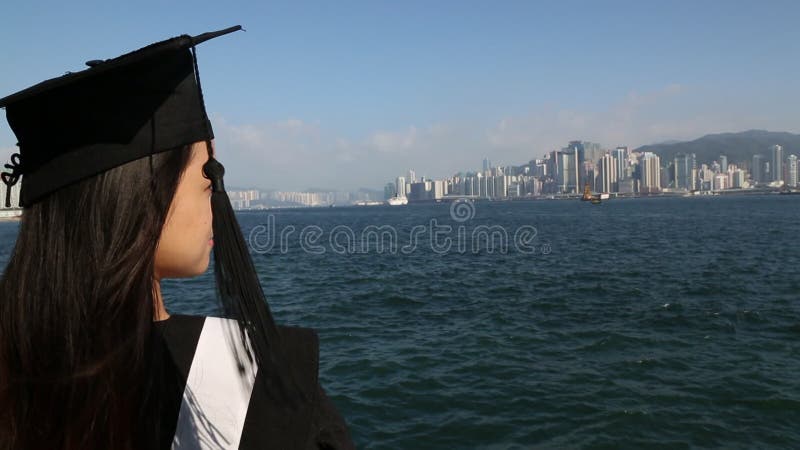 Mulher asiática colocou a tampa da graduação no horizonte hong kong kong na frente da água