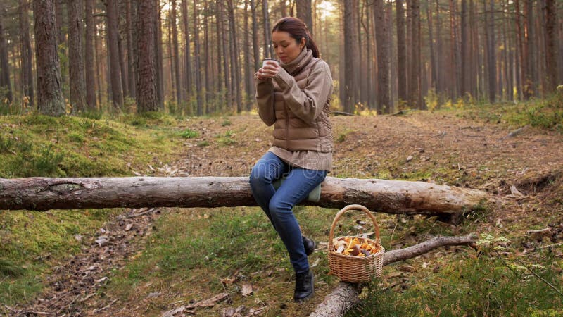 Mulher asiática com cogumelos bebendo chá na floresta