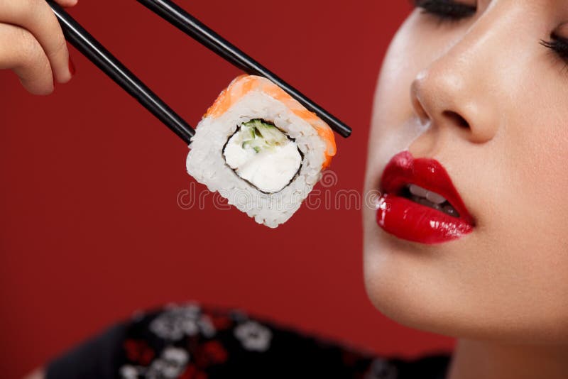 Mulher asiática com sushi que come o sushi e os rolos em um fundo vermelho Venda do sushi de Black Friday imagens de stock royalty free Mulher asiática com sushi que come o sushi e os rolos em um fundo vermelho Venda do sushi de Black Friday imagens de stock royalty free