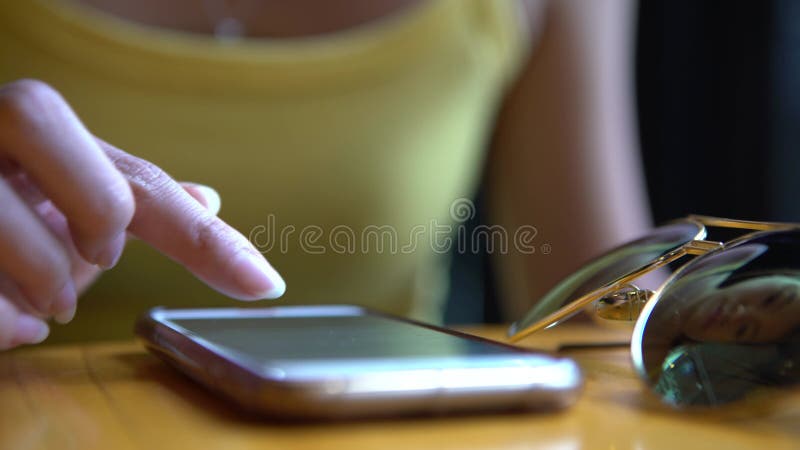 Mulher asiática de 4k usando smartphone toca a tela na mesa do café.