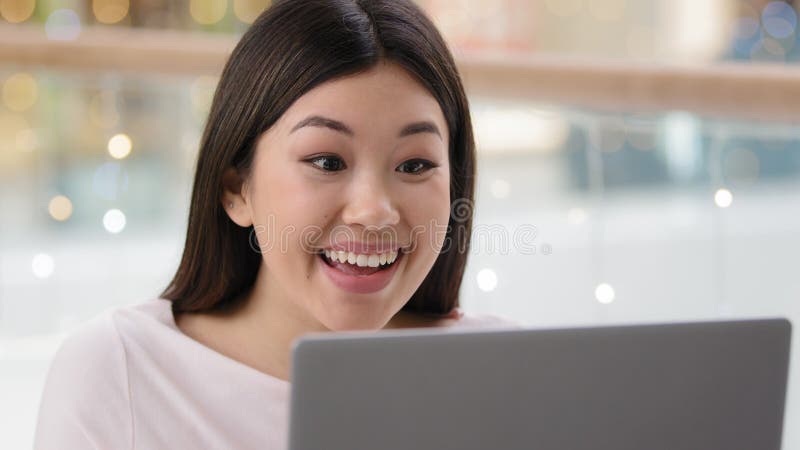 Mulher asiática desregrada ganha o objetivo triunfo diz uau sente-se feliz olhando para a tela do laptop. menina coreana