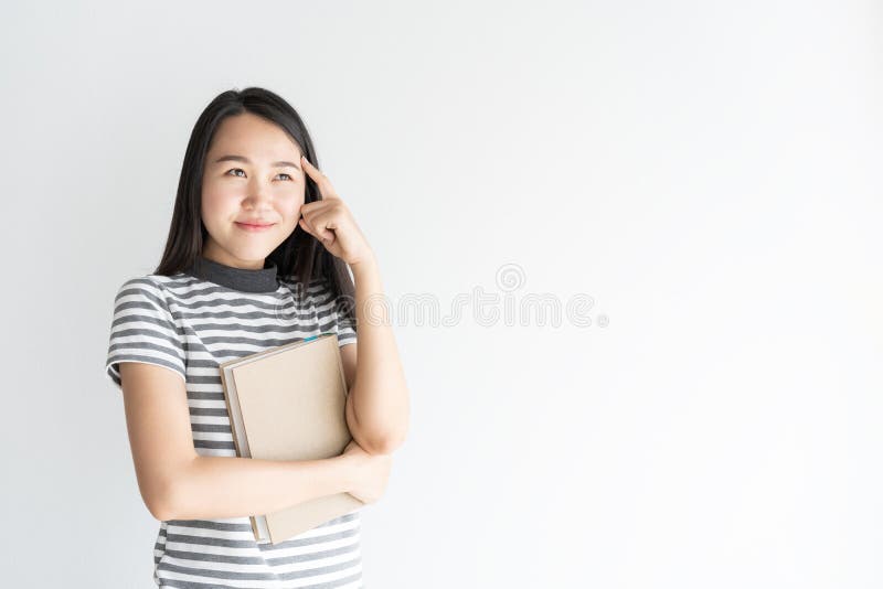 Mulher asiática do retrato que pensa e que guarda o caderno no espaço branco do fundo e da cópia imagens de stock royalty free Mulher asiática do retrato que pensa e que guarda o caderno no espaço branco do fundo e da cópia imagens de stock royalty free