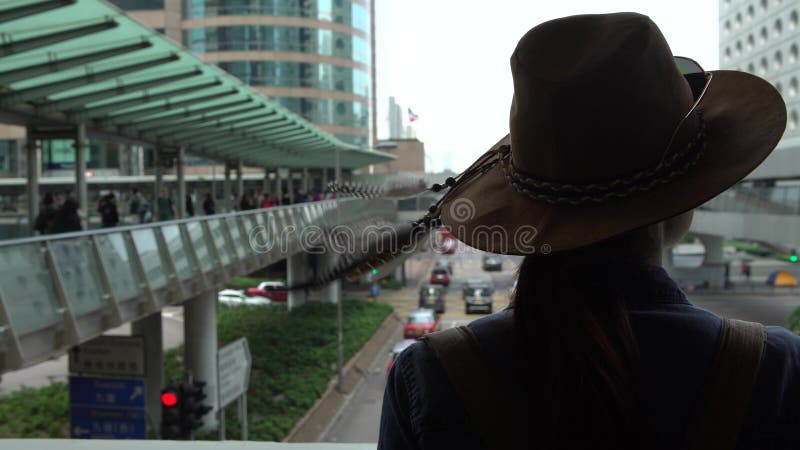 a mulher asiática do turista 4K veste um chapéu na ponte pedestre de Hong Kong Central