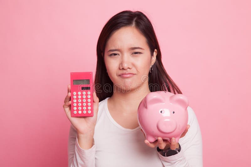Mulher asiática infeliz com calculadora e mealheiro fotos de stock royalty free