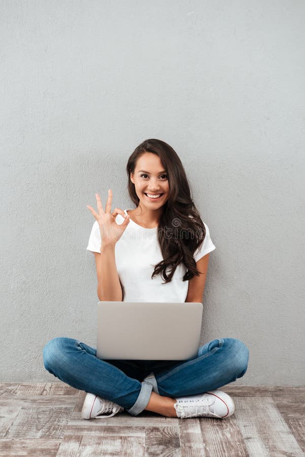 Mulher asiática nova alegre que trabalha no laptop imagem de stock Mulher asiática nova alegre que trabalha no laptop imagem de stock