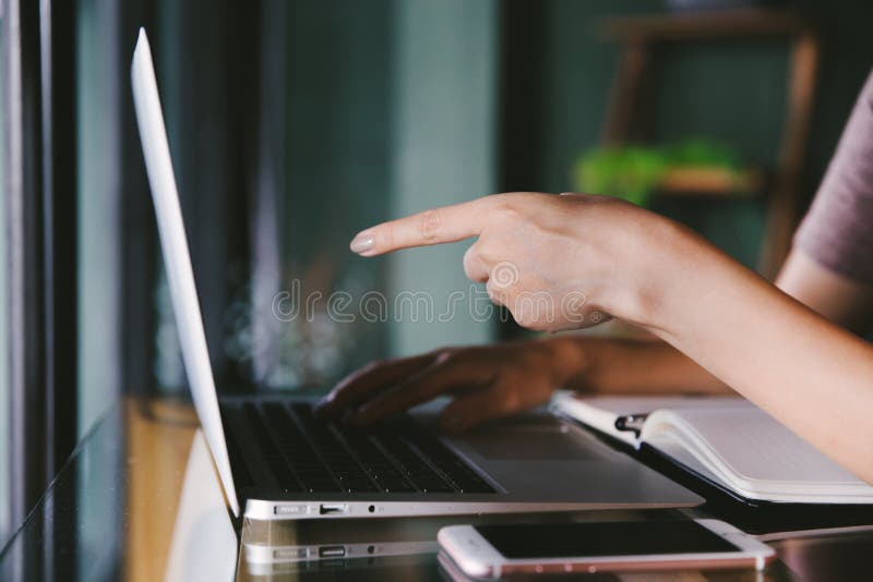 Mulher asiática nova bonita que trabalha em uma cafetaria com portátil do computador foto de stock Mulher asiática nova bonita que trabalha em uma cafetaria com portátil do computador foto de stock