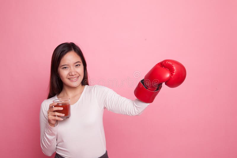 Mulher asiática nova com suco de tomate e luva de encaixotamento fotos de stock