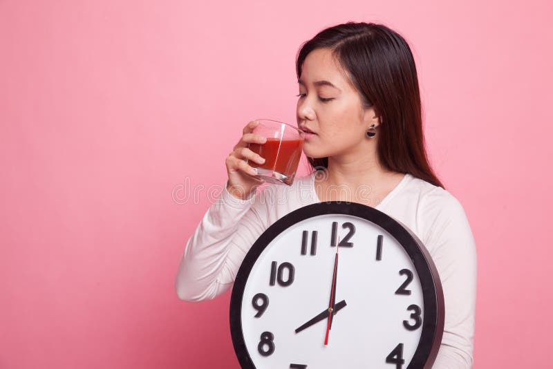 Mulher asiática nova com suco e pulso de disparo de tomate imagem de stock
