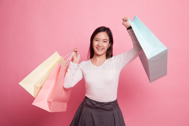 Mulher asiática nova feliz com saco de compras. Mulher asiática nova feliz com o saco de compras no fundo cor-de-rosa
