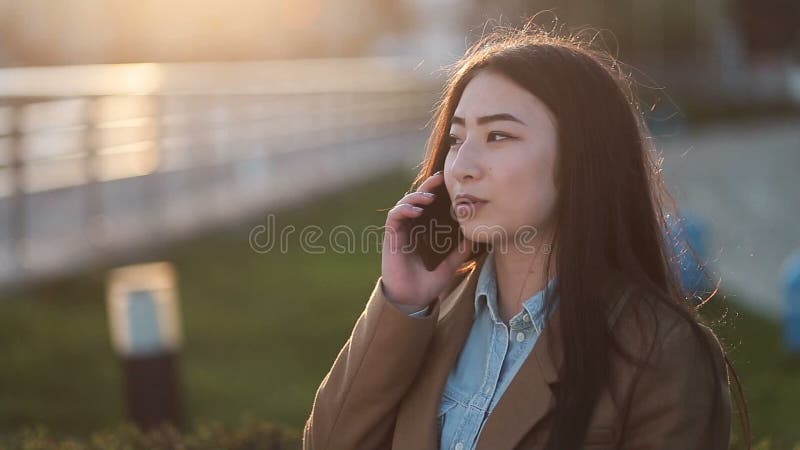 Mulher asiática nova positiva que fala no telefone celular