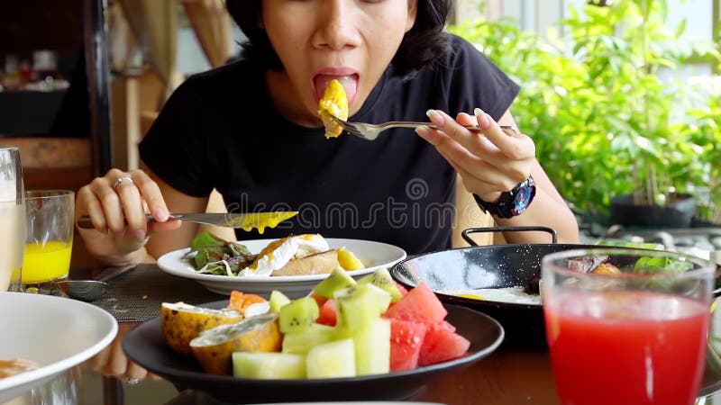Mulher asiática nova que tem o almoço no restaurante