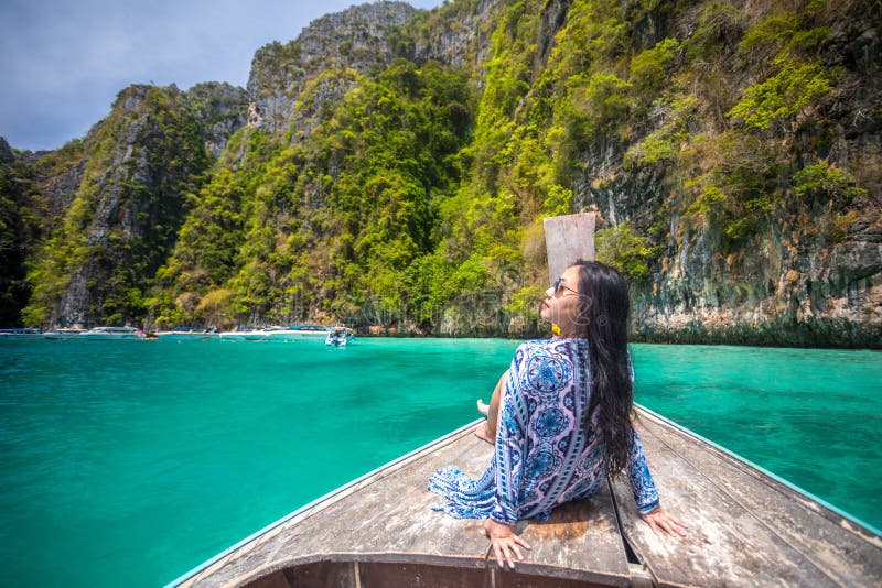 A mulher asiática nova relaxa no barco da cauda longa na baía do Maya imagens de stock A mulher asiática nova relaxa no barco da cauda longa na baía do Maya imagens de stock