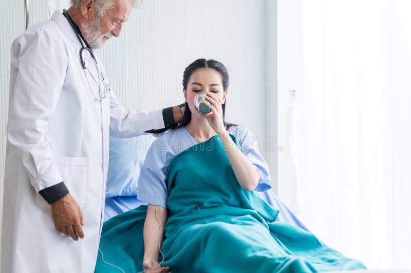 A mulher asiática paciente que toma um doutor da medicina e do homem ajudou-lhe no hospital foto de stock A mulher asiática paciente que toma um doutor da medicina e do homem ajudou-lhe no hospital foto de stock