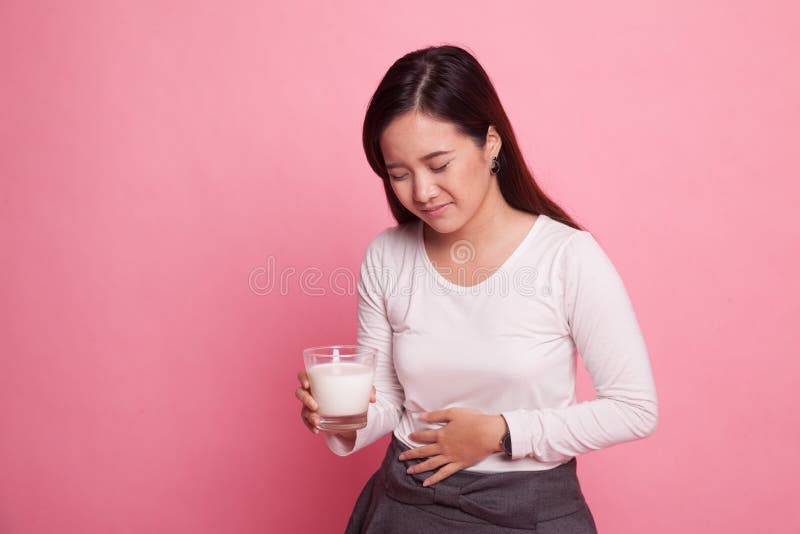 A mulher asiática que bebe um vidro do leite obteve a dor de estômago fotos de stock