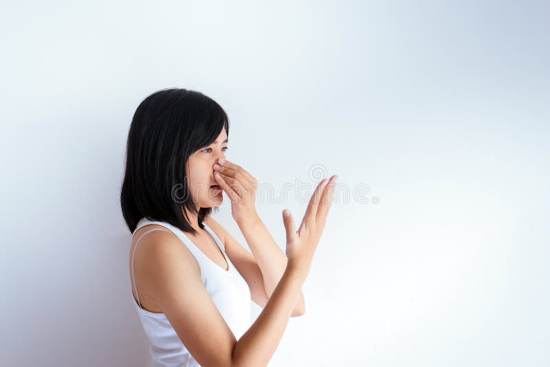 A mulher asiática que cobre seu nariz e cheira sua respiração com upter da mão acorda, cheiro mau foto de stock A mulher asiática que cobre seu nariz e cheira sua respiração com upter da mão acorda, cheiro mau foto de stock