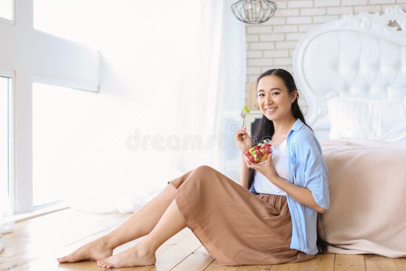 Mulher asiática que come a salada de fruto saudável em casa imagens de stock royalty free Mulher asiática que come a salada de fruto saudável em casa imagens de stock royalty free