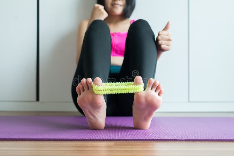 Mulher asiática que usa o elástico para a massagem que estica o dedo do pé com grampo e dor foto de stock Mulher asiática que usa o elástico para a massagem que estica o dedo do pé com grampo e dor foto de stock