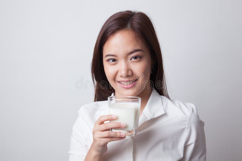 Mulher asiática saudável que bebe um vidro do leite