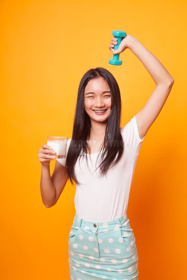 Mulher asiática saudável que bebe um vidro do leite e do peso