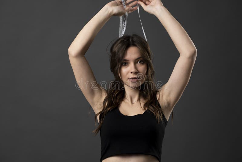 Brunette attractive woman in a underwear looks in a camera while holds white measuring tape around a head. Health care and healthy nutrition. Perfect slim body. Brunette attractive woman in a underwear looks in a camera while holds white measuring tape around a head. Health care and healthy nutrition. Perfect slim body