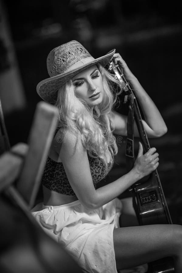 A mulher atrativa com olhar do país, disparou dentro, estilo country americano Menina com o chapéu e a guitarra de vaqueiro da pa fotos de stock A mulher atrativa com olhar do país, disparou dentro, estilo country americano Menina com o chapéu e a guitarra de vaqueiro da pa fotos de stock