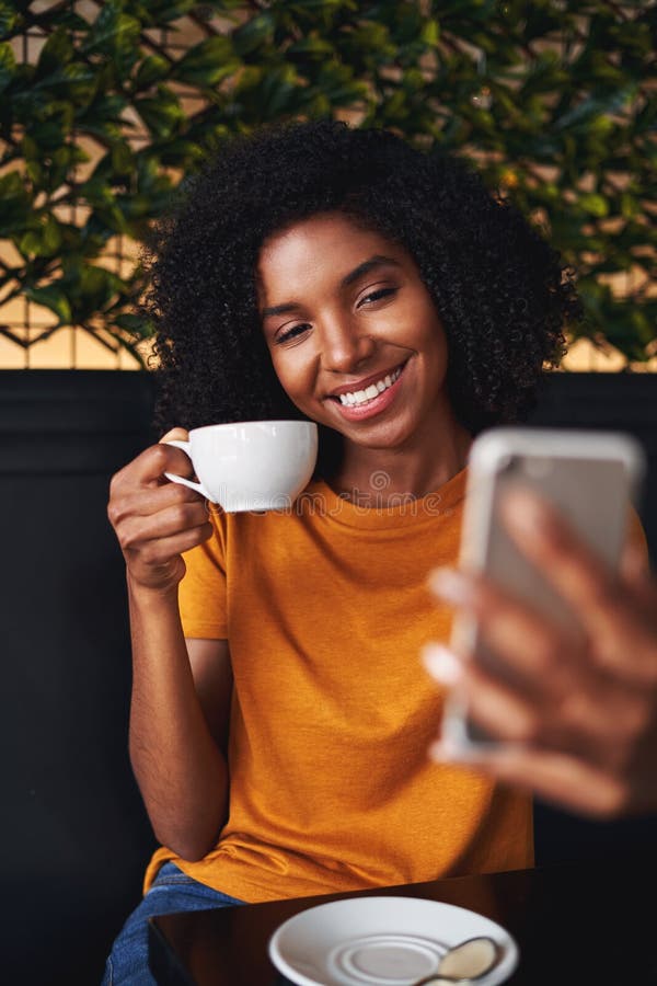 Mulher atrativa no selfie das tomadas da roupa ocasional em uma cafetaria fotos de stock Mulher atrativa no selfie das tomadas da roupa ocasional em uma cafetaria fotos de stock