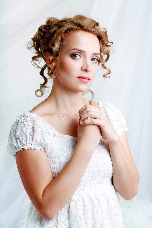 Beautiful woman with romantic bride hairstyle wearing in white wedding dress posing in interior apartment. Beautiful woman with romantic bride hairstyle wearing in white wedding dress posing in interior apartment