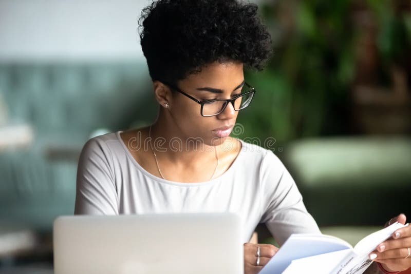 Mulher bonita africana concentrada que estuda lendo um livro imagem de stock royalty free Mulher bonita africana concentrada que estuda lendo um livro imagem de stock royalty free