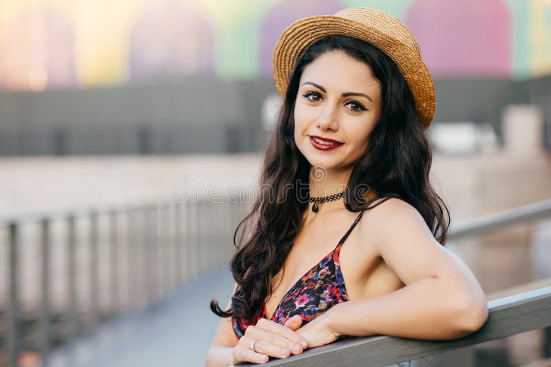 Mulher bonita com cabelo longo escuro, chapéu e vestido vestindo do verão da aparência atraente que têm a excursão na cidade gran fotografia de stock Mulher bonita com cabelo longo escuro, chapéu e vestido vestindo do verão da aparência atraente que têm a excursão na cidade gran fotografia de stock