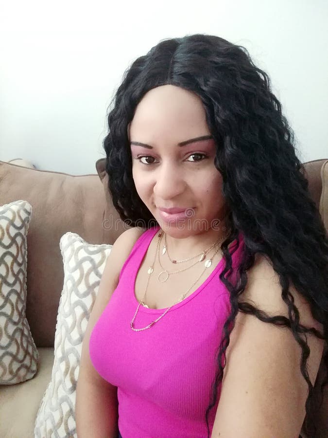 Mulher bonita com o cabelo ondulado que senta-se em um sofá fotografia de stock Mulher bonita com o cabelo ondulado que senta-se em um sofá fotografia de stock