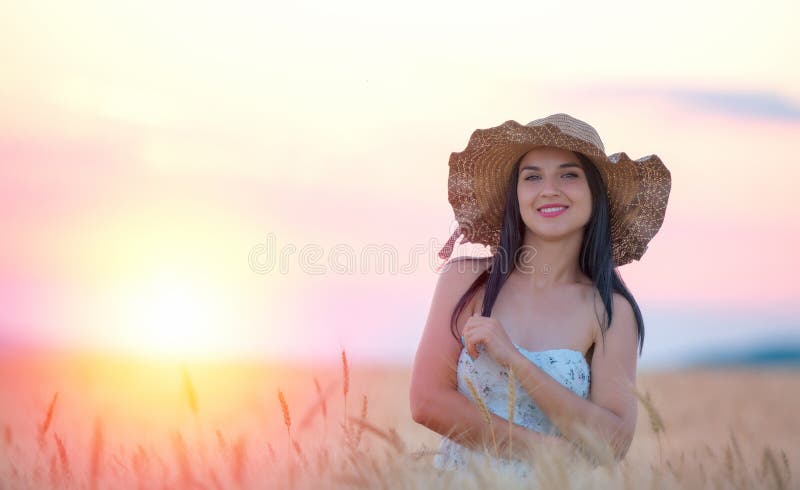 Mulher bonita com o chapéu do verão no campo de trigo no por do sol fotos de stock Mulher bonita com o chapéu do verão no campo de trigo no por do sol fotos de stock