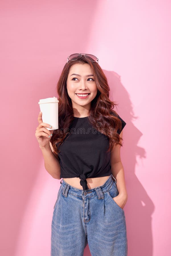 Mulher bonita da forma com o copo de caf? que veste a roupa preta sobre o fundo cor-de-rosa colorido foto de stock Mulher bonita da forma com o copo de caf? que veste a roupa preta sobre o fundo cor-de-rosa colorido foto de stock