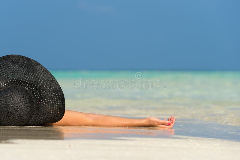 Mulher bonita em um chapéu que encontra-se em uma praia tropical foto de stock Mulher bonita em um chapéu que encontra-se em uma praia tropical foto de stock