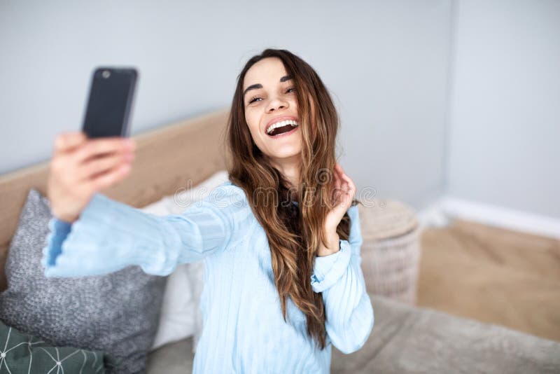 A mulher bonita faz em casa o selfie no telefone celular imagens de stock A mulher bonita faz em casa o selfie no telefone celular imagens de stock