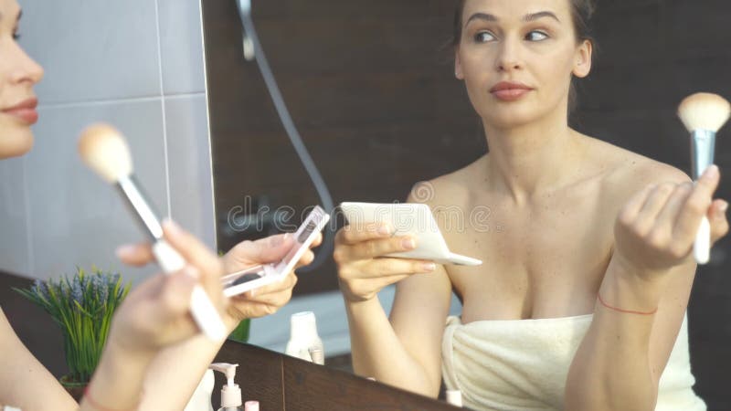 Mulher Bonita E Satisfeita Olhando Para O Espelho No Banheiro, Sentindo-se  Bonita E Atraente, Menina Feliz Usando Roupão Branco Tocando A Pele Lisa  Perfeita Do Rosto, Desfrutando Da Rotina De Cuidados Com