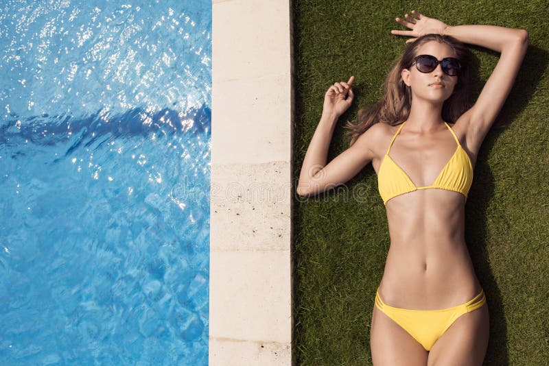 Mulher bonita magro nova no banho de sol amarelo do biquini imagens de stock Mulher bonita magro nova no banho de sol amarelo do biquini imagens de stock