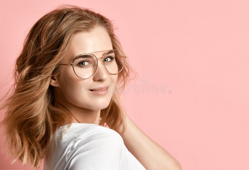Mulher bonita no t-shirt branco e nos vidros modernos que levantam no rosa imagem de stock royalty free Mulher bonita no t-shirt branco e nos vidros modernos que levantam no rosa imagem de stock royalty free