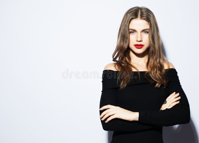 Mulher bonita nova que veste o vestido preto que levanta sobre o fundo branco fotografia de stock Mulher bonita nova que veste o vestido preto que levanta sobre o fundo branco fotografia de stock