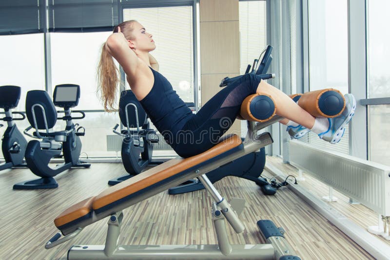 Mulher bonita que faz o exercício da aptidão da imprensa no gym do esporte imagem de stock Mulher bonita que faz o exercício da aptidão da imprensa no gym do esporte imagem de stock